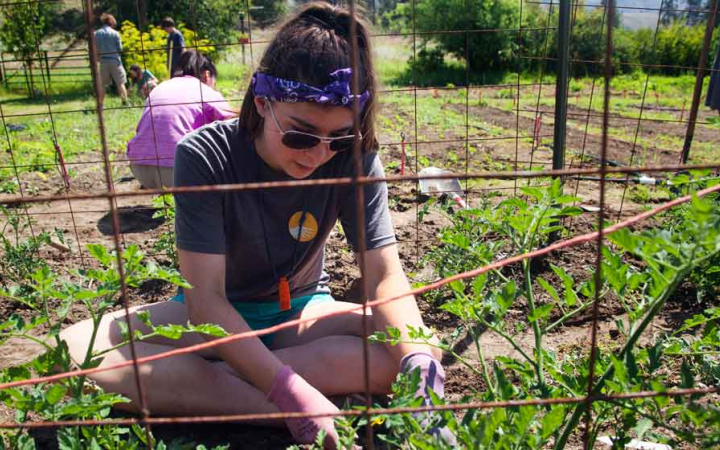 a teen works in a garden during a service project with outward bound